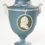 A pale blue vase with white trim and carved face