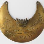 A crescent shaped piece of shiny brass with words and images carved into it