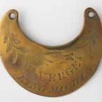 A crescent shaped piece of shiny brass with words and images carved into it