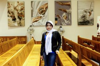Rim standing between the pews inside her church.