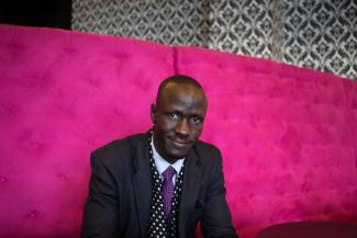 Deng sitting with a pink backdrop.