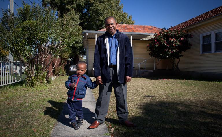 Image of Theophile and his son in front of their house.