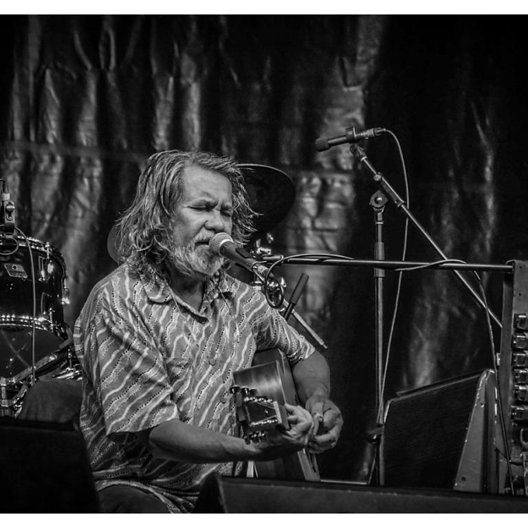 Image of Stephen Pigram playing ukulele and singing into a microphone